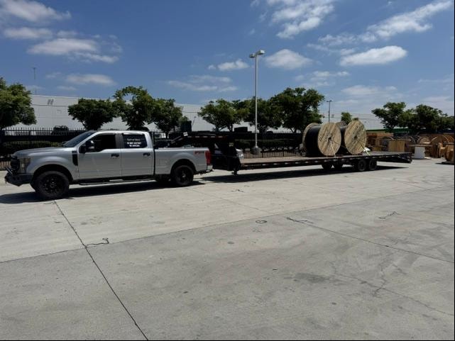 Silver truck hauling cable reels on flatbed